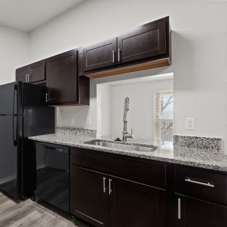 Encino Park Apartments designer kitchen with dark wood custom cabinets and granite countertops