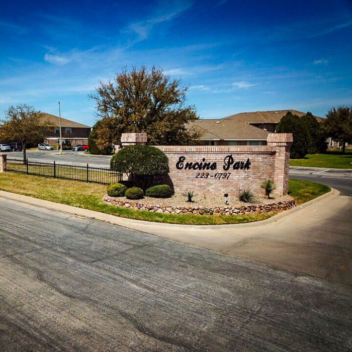 Encino Park apartments exterior featuring stonework gate and signage