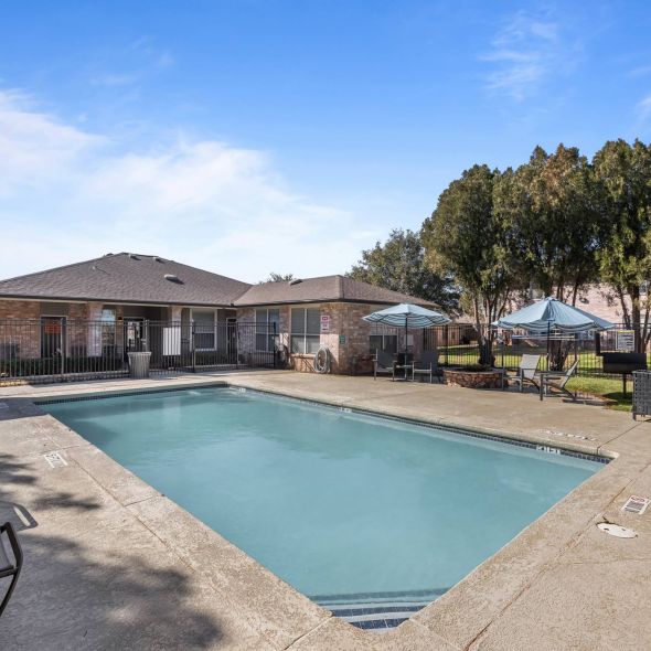 Encino Park apartments community swimming pool surrounded by clubhouse and lounge chairs